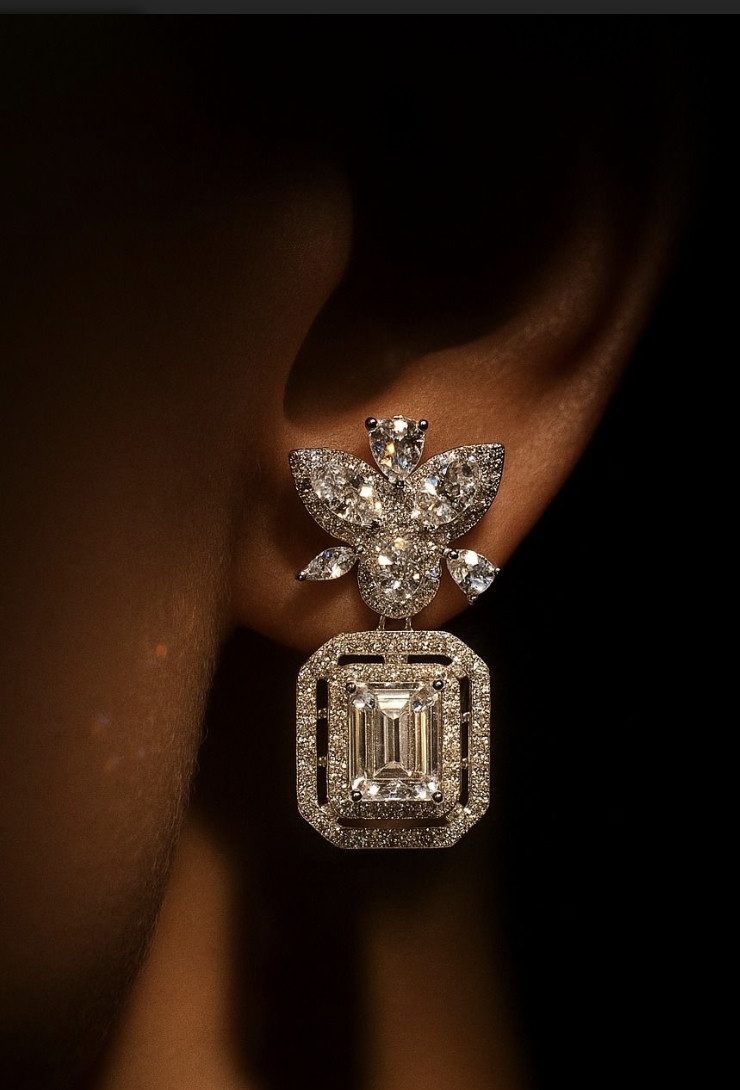 Emerald-cut diamond drop earring with floral cluster top, worn against a dark background